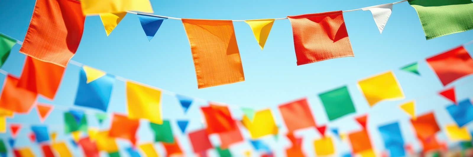 Colorful flags decorate a vibrant outdoor space during a sunny festival celebration
